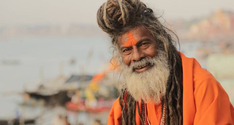 Portrait d'un Sadhu souriant avec le front peint de cendre et une longue barbe blanche sur les ghats du Gange.