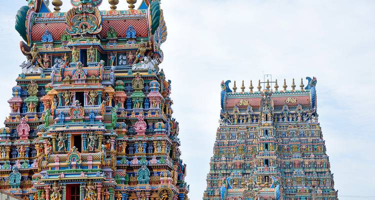 Die lebhaft bemalten Gopurams des Meenakshi-Tempels erheben sich gegen einen blassen Himmel.