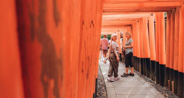 Deux femmes font une pause à l'intérieur du tunnel de torii écarlates du Sanctuaire Fushimi Inari à Kyoto.