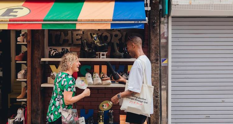 Des voyageurs discutent à l'extérieur d'une boutique de chaussures colorée sur une rue animée du Japon.