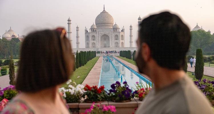 Wazig stel bewondert de Taj Mahal vanaf een met bloemen omzoomd uitzichtpunt bij schemering.
