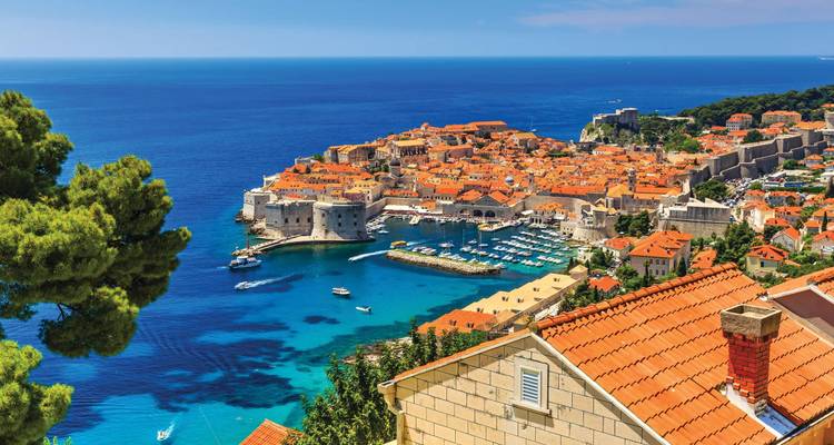 Weitläufiger Blick über Dubrovniks terrakottafarbene Dächer, mittelalterliche Mauern und das azurblaue Adriatische Meer von einem erhöhten Aussichtspunkt aus.