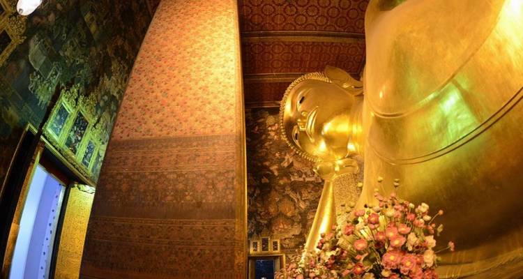 Perspective intérieure du temple du Bouddha couché de Bangkok montrant la massive statue dorée et les murales complexes.