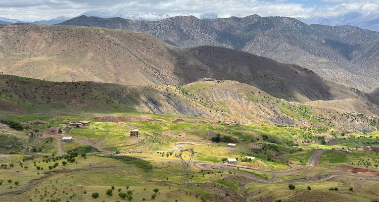 Sweeping view of patchwork green valleys and rugged High Atlas mountains dotted with tiny villages.