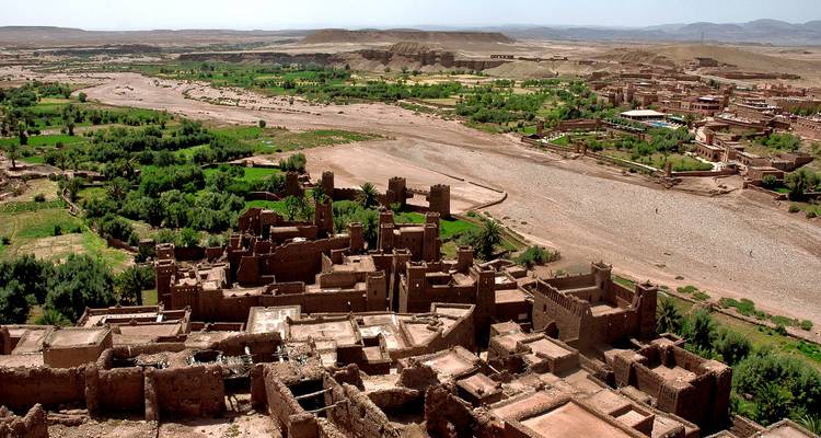 Panoramic view from above Ait Benhaddou’s mud-brick ksar overlooking the dry riverbed and verdant oasis.