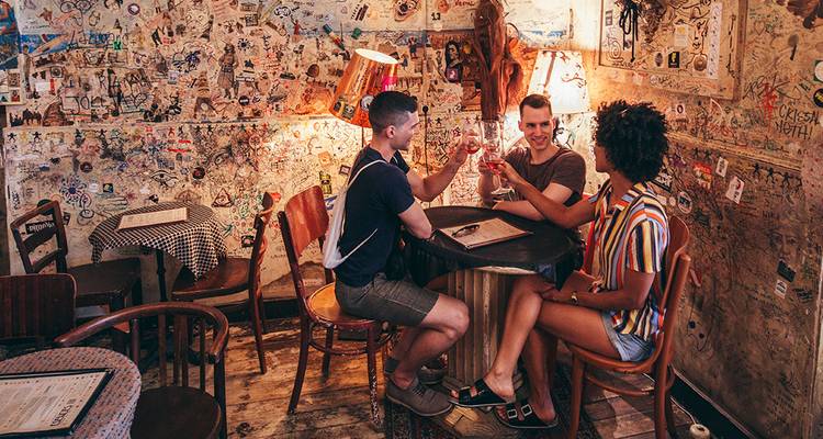 Vrienden heffen hun glas in een excentrieke, met graffiti bedekte ruin pub versierd met verschillende lampen.