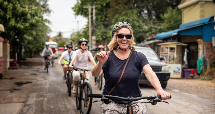 Smiling cyclist leads a small bike tour along a rural Cambodian road.