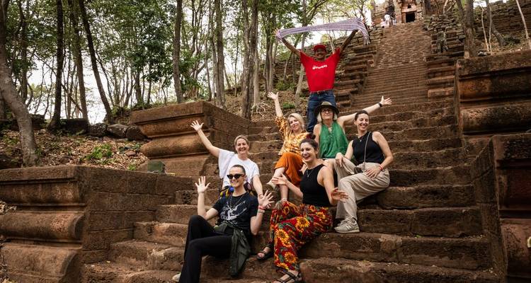 Group poses playfully on ancient stone steps of a jungle temple ruin.