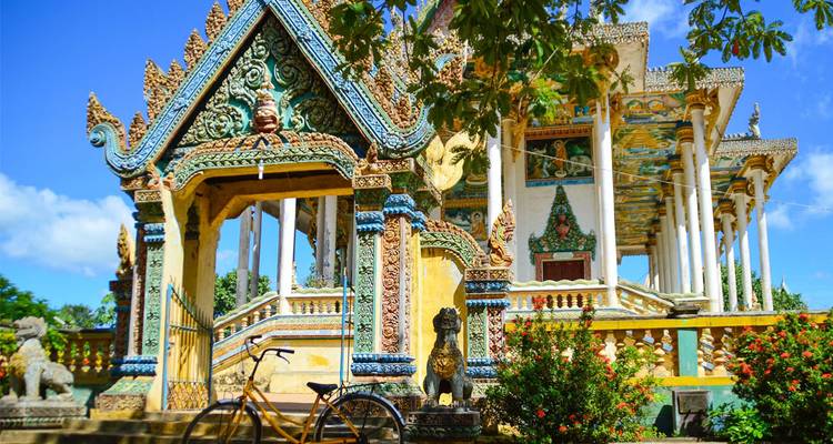 Ornately decorated Buddhist temple with colorful carvings and a bicycle in front.