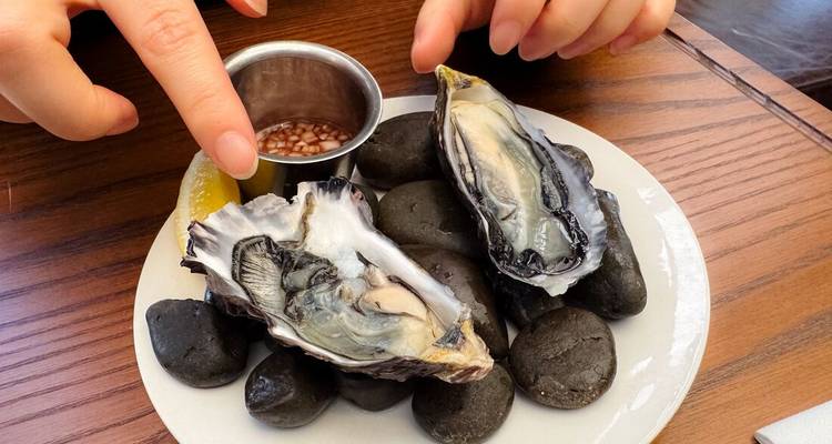 Fresh raw oysters on a plate of river stones with lemon and shallot vinaigrette