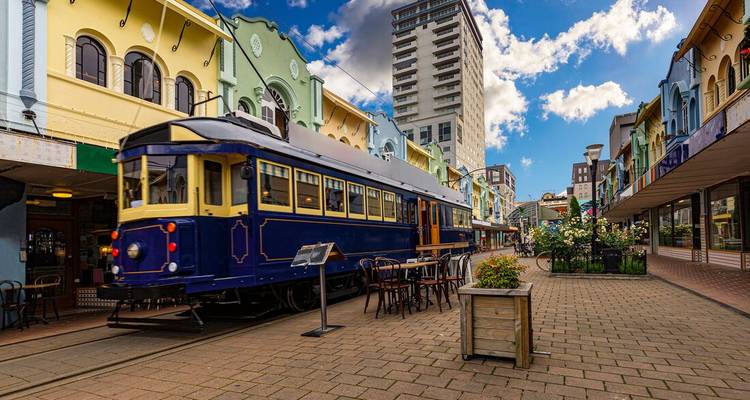 Heritage blue tram on a colourful pedestrian street lined with cafés and historic buildings