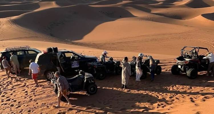 Véhicules 4x4 et quads garés sur une dune de sable alors que les voyageurs se préparent pour une promenade