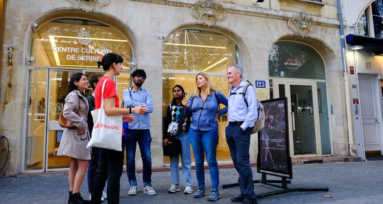 Guide touristique parlant à des voyageurs devant la devanture d'un centre culturel urbain
