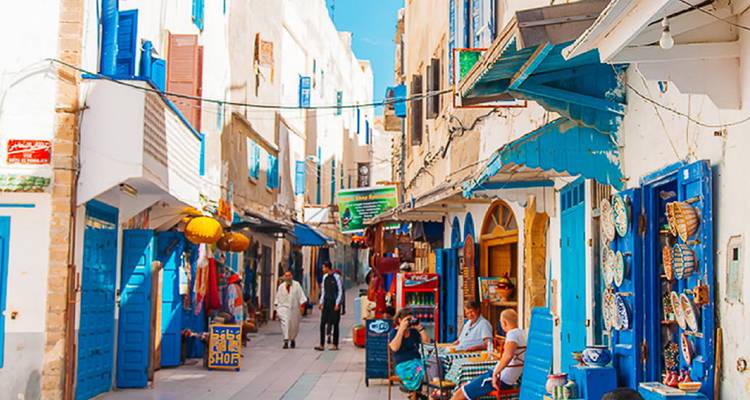 Ruelle étroite et colorée dans la médina d'Essaouira bordée de portes bleues et de petits commerces locaux.