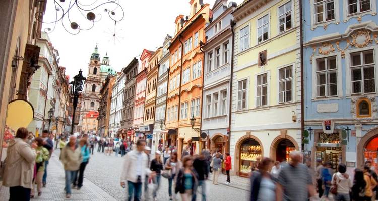 Rue piétonne animée bordée de bâtiments historiques colorés dans la Vieille Ville de Prague.
