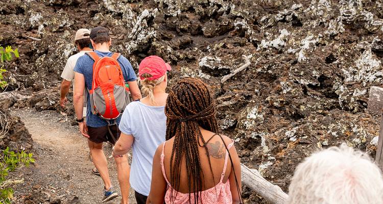 Reisende, die auf einer Vulkangesteinsstrecke auf den Galápagos-Inseln wandern.