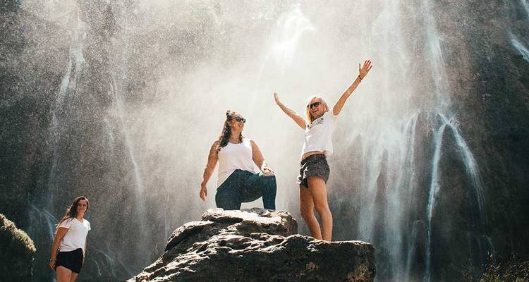 Groupe de voyageurs célébrant sous les embruns d'une puissante cascade.