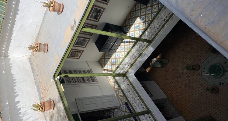 Looking down into a traditional riad courtyard with geometric floor tiles and central fountain.