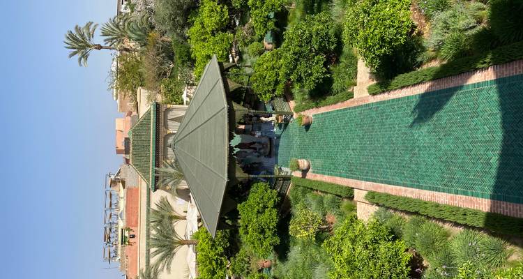 Long green-tiled path leads to a garden pavilion surrounded by citrus trees and lawns.