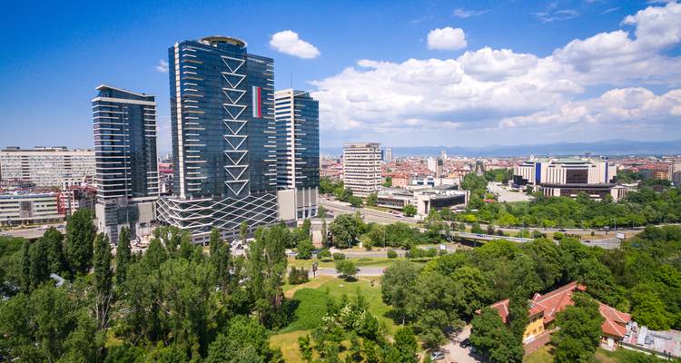 Les immeubles de grande hauteur en verre moderne dominent les parcs verdoyants et les toits résidentiels de Sofia lors d'une belle journée d'été ensoleillée.