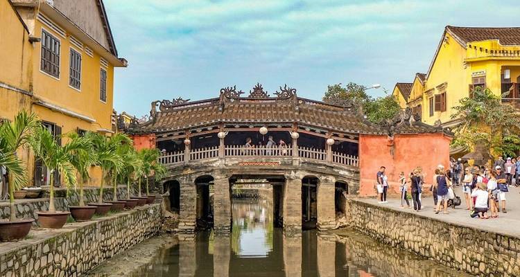Front view of Japanese Covered Bridge spanning a narrow canal with tourists nearby.