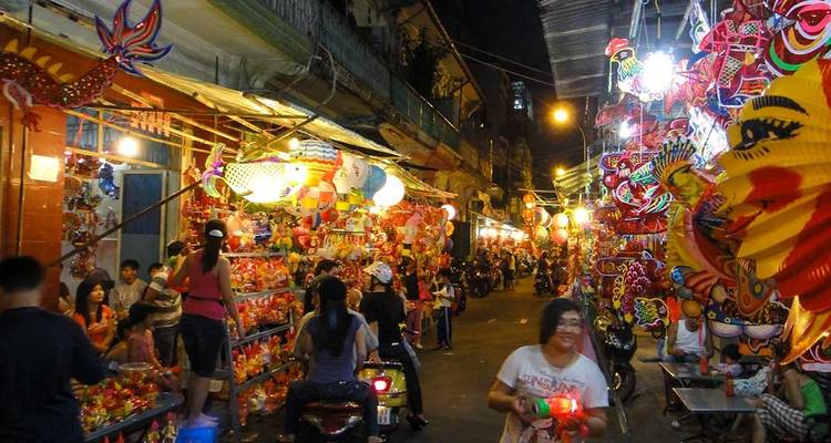 Vibrant night market alley filled with lanterns, toys, and crowds under warm lights.