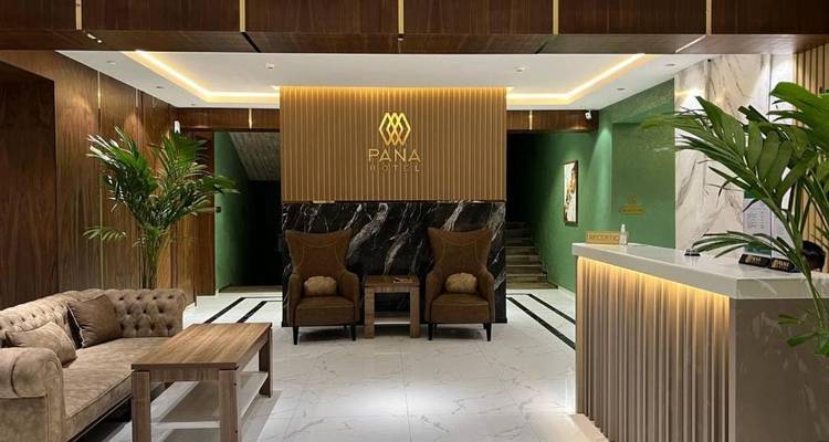 Stilvolle Hotellobby mit grünen Akzentwänden, Marmor-Empfangstheke, moderner Beleuchtung und komfortablen Sitzmöglichkeiten.