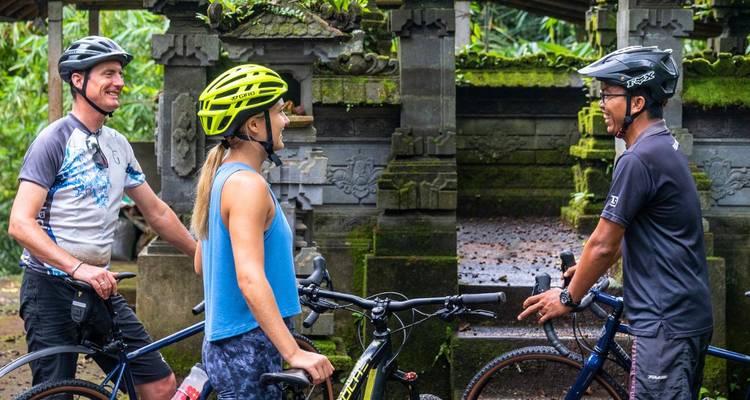 Les cyclistes discutent à côté d'une porte de temple en pierre richement sculptée couverte de mousse.