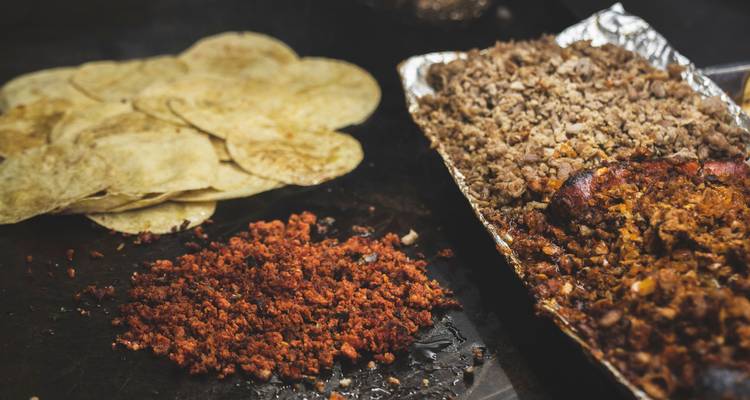 Plancha de comida callejera con tortillas, chorizo picado y carnes sazonadas listos para tacos