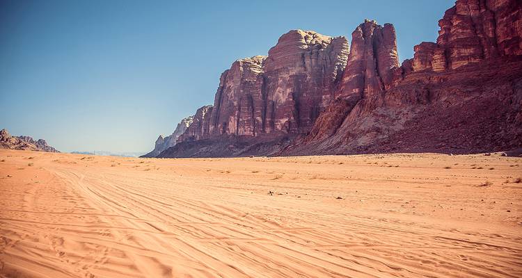 Amplio tramo de arena roja y acantilados de arenisca que se alzan en el desierto de Wadi Rum en Jordania.