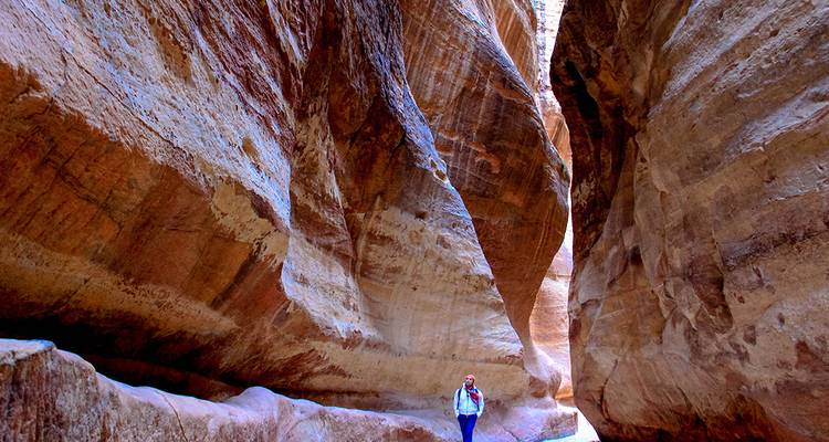 Un viajero camina por el estrecho cañón Siq, con paredes altas, que conduce a Petra.