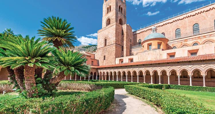 Jardin de cloître paisible avec palmiers à l'abbaye de Monreale sous un ciel bleu dégagé.