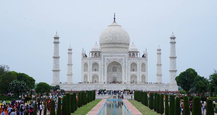 Klassische symmetrische Ansicht des Taj Mahal und des Spiegelungsbeckens, umgeben von Besuchern.
