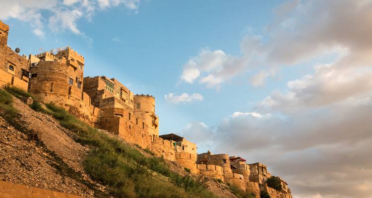 Goldene Sandsteinfestungen erhebt sich einen steilen Hügel unter einem dramatischen blauem Himmel mit Wolken in Rajasthan hinauf.