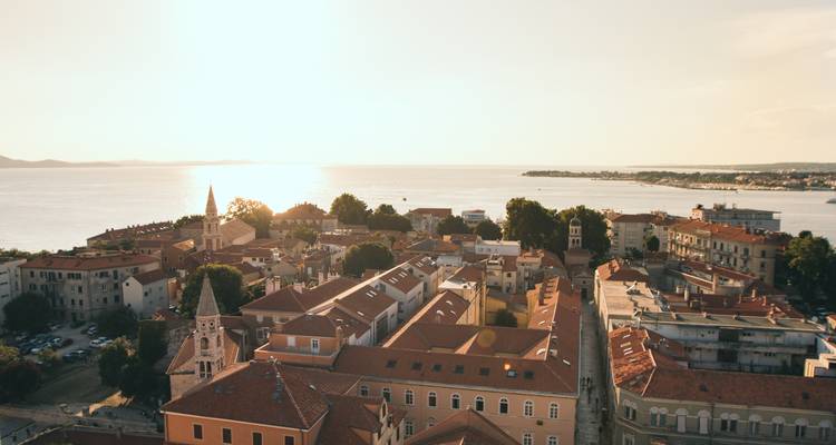 La luz del atardecer sobre los tejados de la ciudad vieja de Zadar junto al tranquilo Mar Adriático.