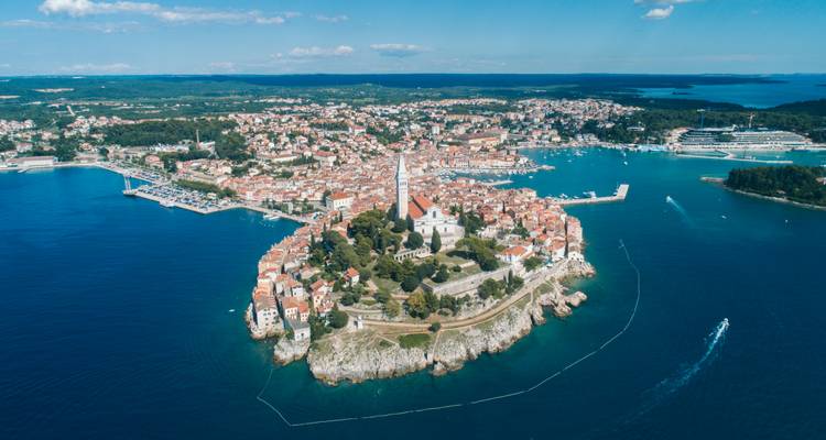 Vista aérea de gran altura de la península de Rovinj rodeada de un mar azul profundo en un día despejado.