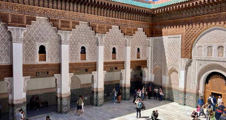 Les visiteurs explorent la cour richement sculptée d'une madrasa historique
