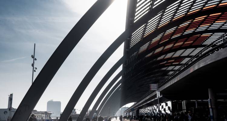 La lumière dramatique filtre à travers le toit en verre arqué d'une gare de transit moderne.