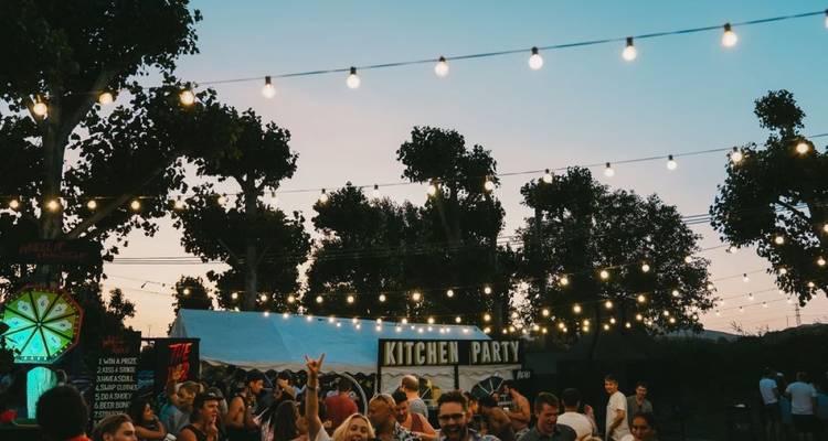 Des personnes sous des guirlandes lumineuses lors d'un événement en plein air.
