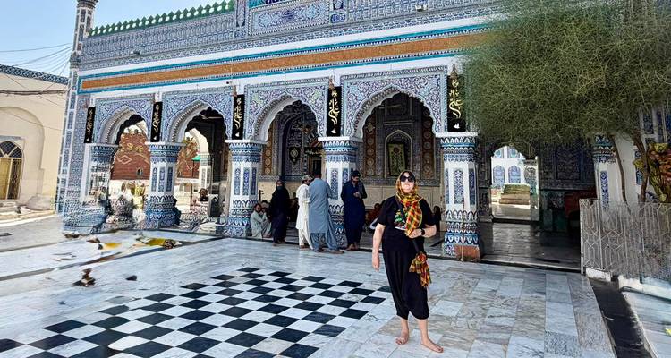 Les visiteurs debout dans la cour en marbre de l'entrée de la mosquée aux carrelages élaborés