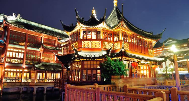Traditional Chinese teahouse in Shanghai's Yuyuan Bazaar glowing with golden lights at night.