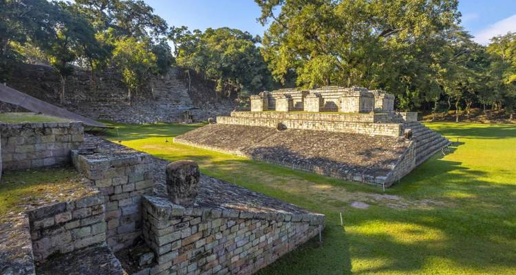 Plateforme de temple pyramidal en pierre sur la place gazonnée du site archéologique de Copán
