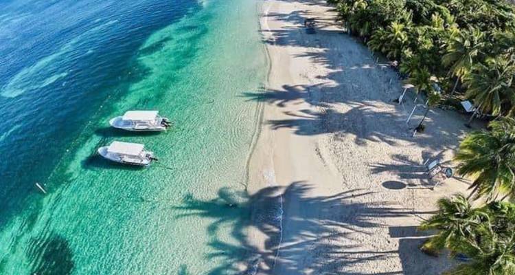 Vue aérienne du rivage turquoise avec plage de sable blanc et deux petits bateaux
