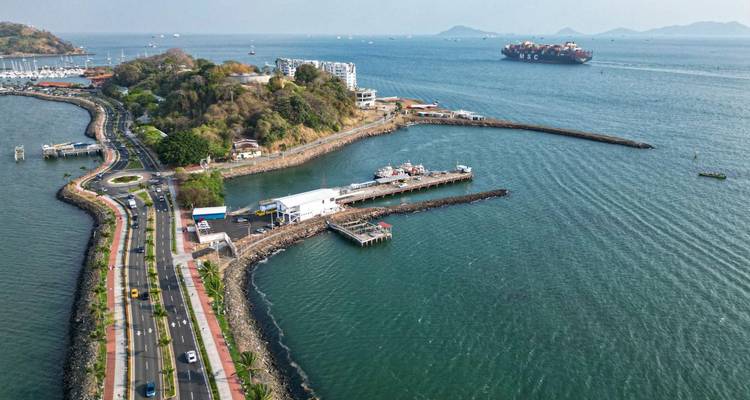 Carretera costera con un puerto deportivo, camino curvo y un gran barco de carga en la bahía cerca de la Ciudad de Panamá.