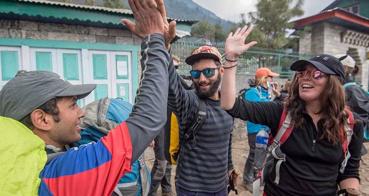 Los trekkers se chocan las manos alegremente en un pueblo de la región del Himalaya.