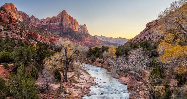 Der Virgin River schlängelt sich bei Sonnenuntergang durch den Zion Canyon mit leuchtend roten Felswänden.