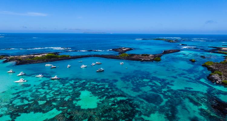 Luftaufnahme von türkisfarbenen Buchten, schwarzem Vulkangestein und ankernden Yachten auf den Galapagos-Inseln