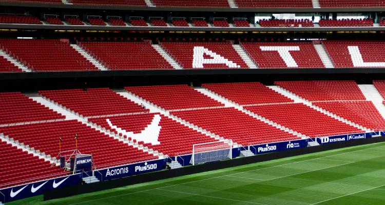 Les gradins rouges vides des niveaux de sièges du stade de football de l'Atlético Madrid avec un terrain de jeu vert luxuriant au premier plan.