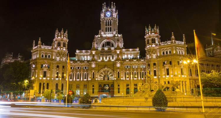 Palacio de Cibeles magnifiquement illuminé la nuit avec les traces lumineuses du trafic passant.