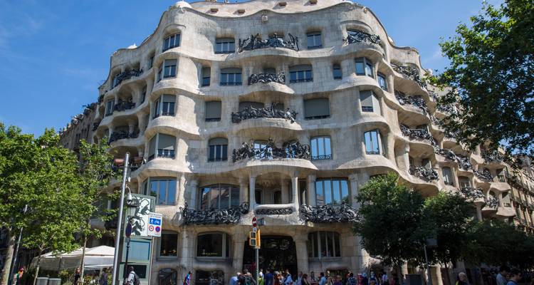 La Casa Milà de Gaudí avec des touristes sur le trottoir sous un ciel bleu dégagé